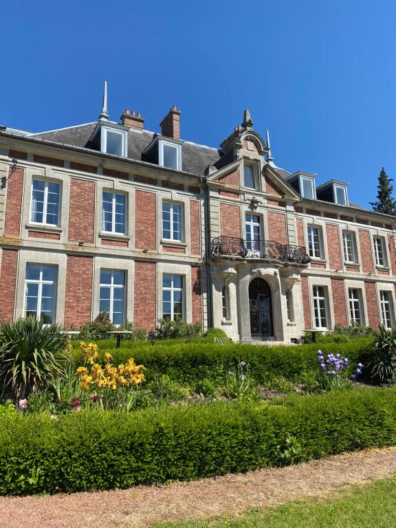 een groot bakstenen gebouw met een tuin ervoor bij Domaine de Vadancourt in Maissemy