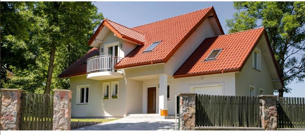 una casa con techo naranja y valla en Grabina Mazury, en Stare Juchy
