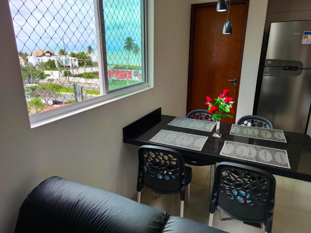 ein Esszimmer mit einem Tisch, Stühlen und einem Fenster in der Unterkunft Apto NOVO de 2 quartos a 50m da praia do bessa in João Pessoa