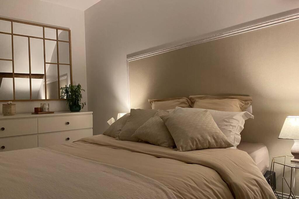 a white bedroom with a large bed with two lamps at Un petit coin sous les toits in Épernay