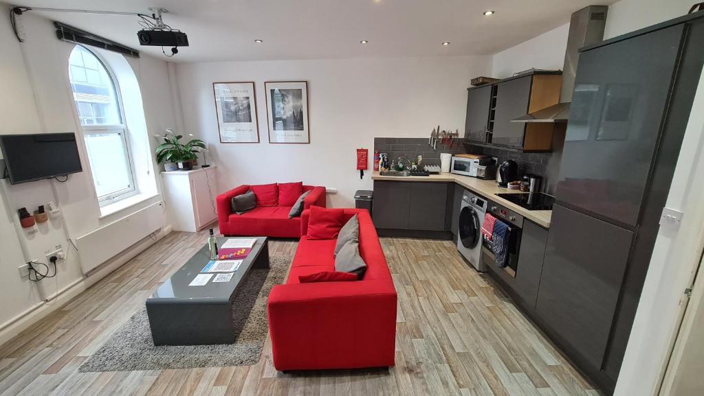 a living room with two red couches and a kitchen at Smart Town Centre Apartments in Northampton