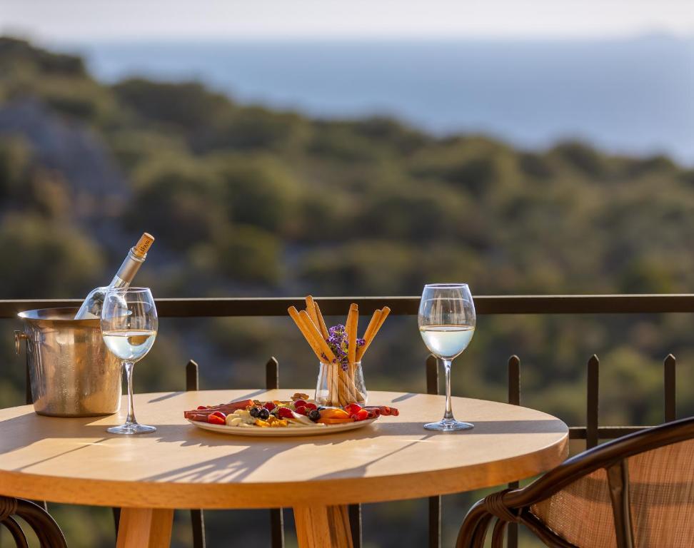 a table with a plate of food and two wine glasses at Hill House Adult Only in Kaş