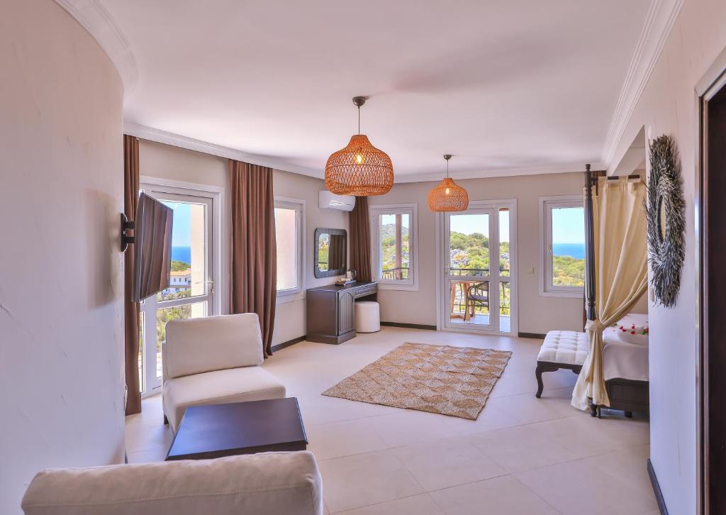 a living room with a couch and chairs and windows at Hill House Adult Only in Kaş