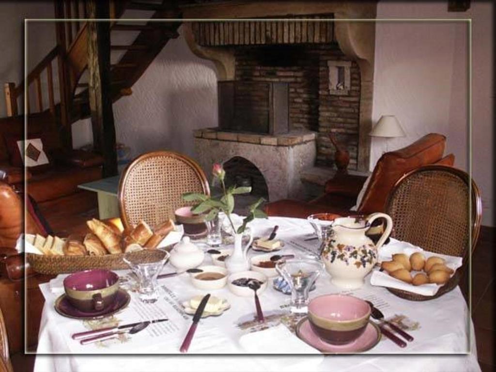 a table with a white table cloth with food and a fireplace at La Croix de Saburin in Quincié-en-Beaujolais