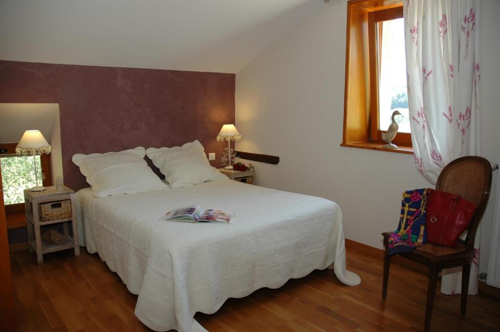 a bedroom with a white bed and a chair at La Croix de Saburin in Quincié-en-Beaujolais