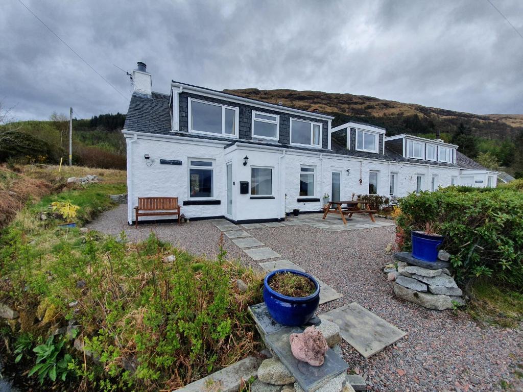 a large white house with a bench in front of it at Sea Otter Cottage in Appin