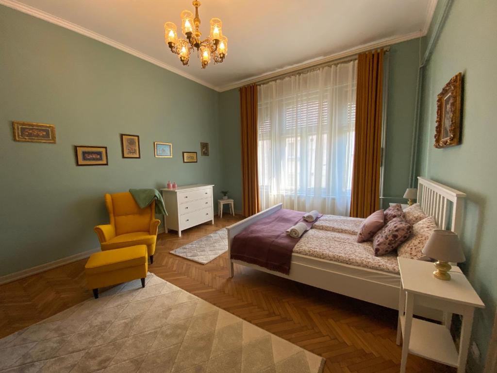 ein Schlafzimmer mit einem Bett, einem Stuhl und einem Kronleuchter in der Unterkunft City Stay Timisoara in Timişoara