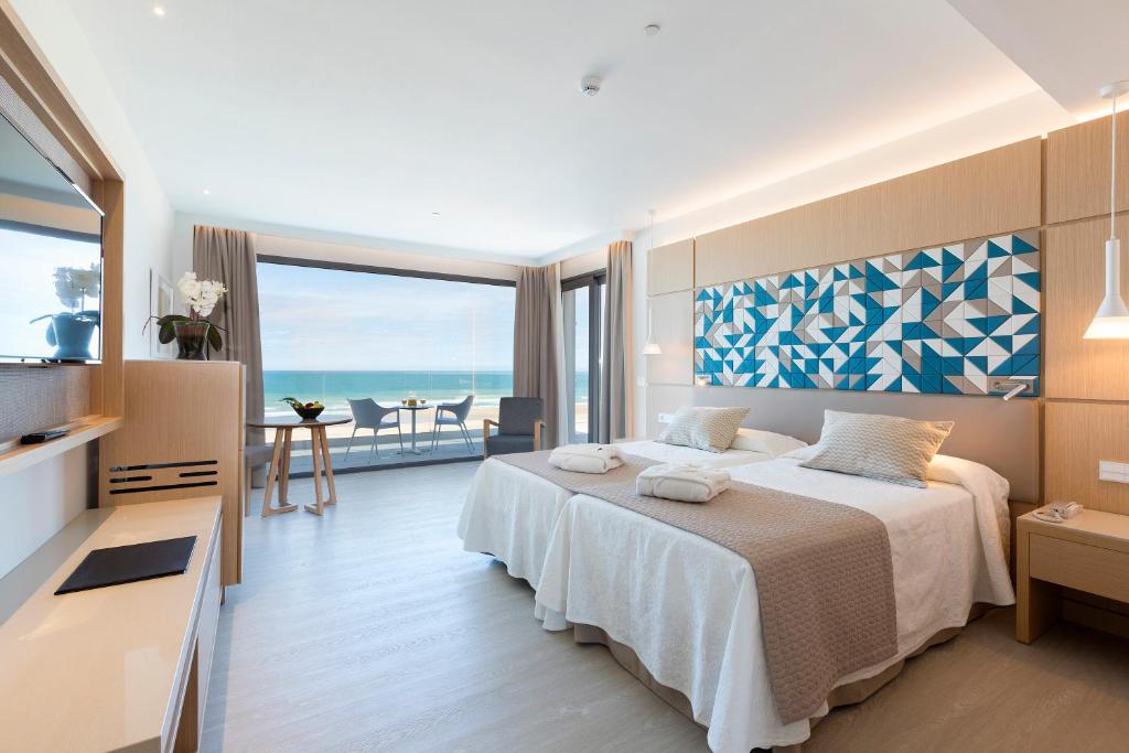 a bedroom with a bed with a view of the ocean at Hipotels Barrosa Park in Chiclana de la Frontera