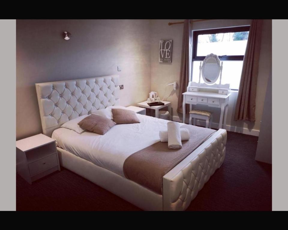 1 dormitorio con 1 cama blanca grande y espejo en The R Inn Hotel, en Desborough