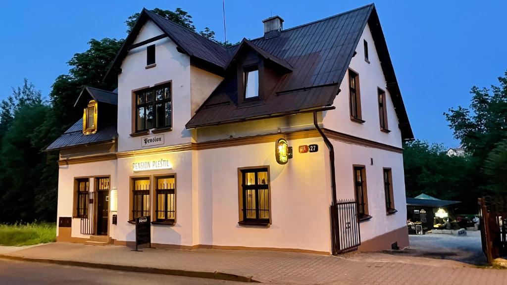 una casa blanca con techo negro en Pension Plestil, en Liberec