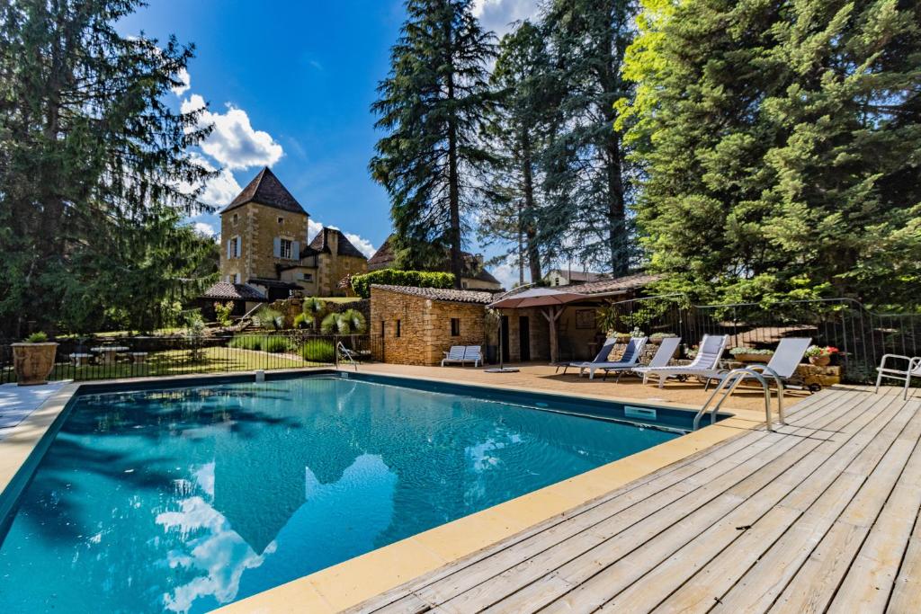 una piscina en una terraza de madera junto a una casa en Villa avec piscine sur le domaine d'un château en Carsac-Aillac