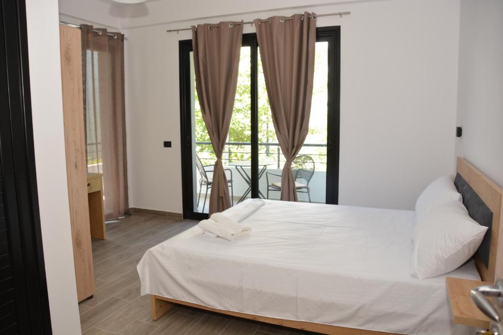 a bedroom with a white bed and a balcony at Lungomare private rooms in Vlorë