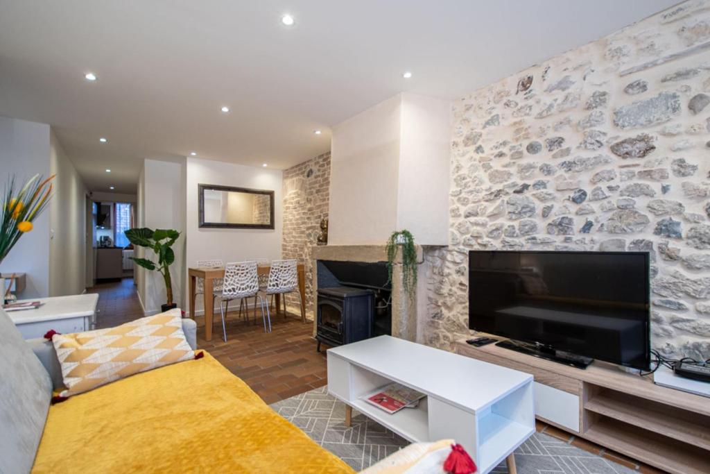 uma sala de estar com televisão e uma parede de pedra em Le Puit Saint Jean 3 - Apartment for 2-4 people em Annecy