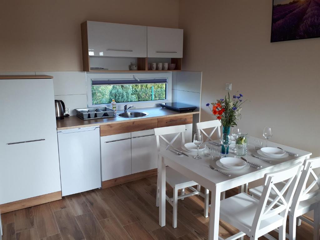 a kitchen with a white table and chairs and a white refrigerator at Domki Anusia Niechorze in Niechorze