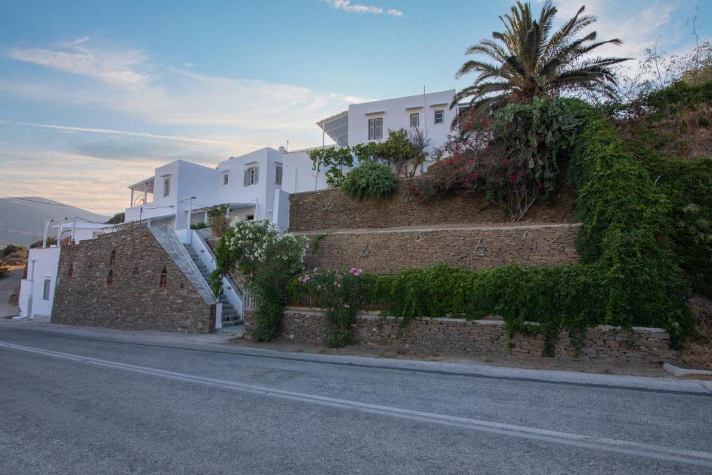 une maison blanche avec des escaliers et un palmier sur le côté d'une rue dans l'établissement Prasini Gonia, à Platis Gialos