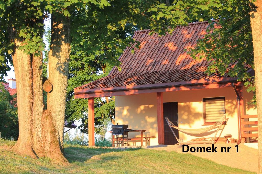 una casa con una hamaca delante en Domki w porcie Zielony Gaj en Mikołajki