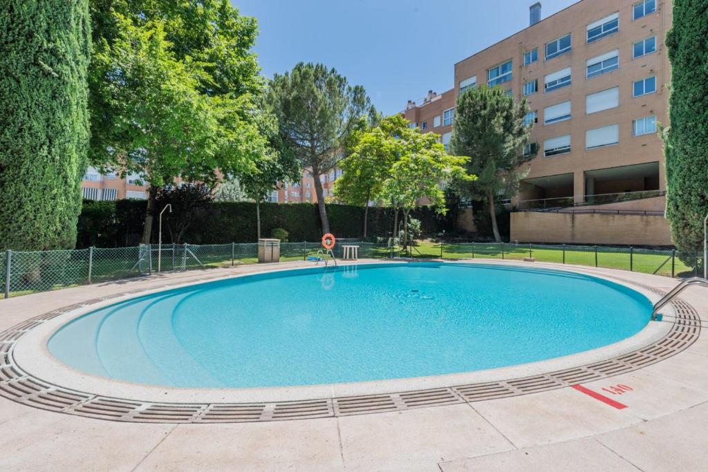 una gran piscina en un patio con árboles y un edificio en Los Robles Stylish & Modern 1 Bedroom Apartment in Madrid Conde Orgaz en Madrid