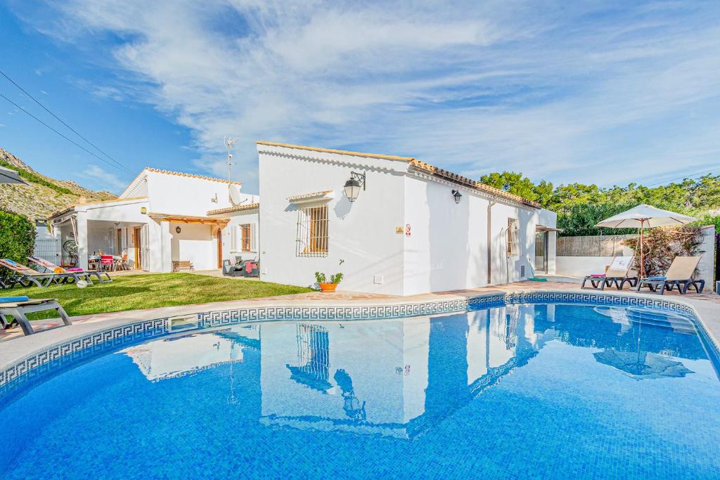 a villa with a swimming pool in front of a house at Chalet Can Singala in Port de Pollensa