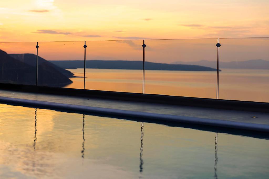 a pool with a view of the water at sunset at Serenity Penthouse in Chalkida