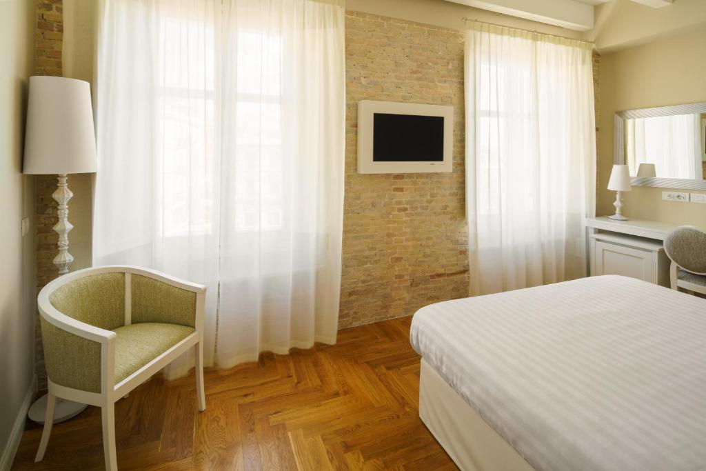 a hotel room with a bed, chair and a television at Boutique Hotel Carlo Felice in Cagliari