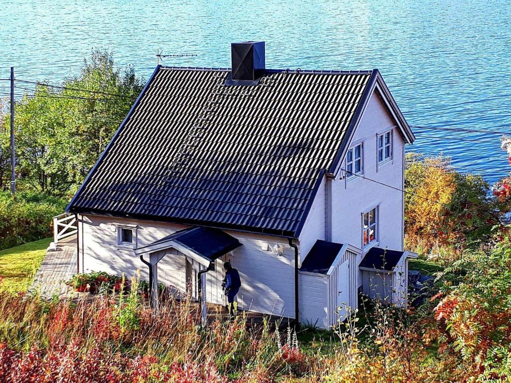 a white house with a black roof next to the water at 6 person holiday home in Olderdalen in Olderdalen