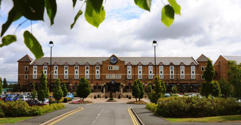 ein großes Backsteingebäude mit einer Uhr auf der Vorderseite in der Unterkunft Village Hotel Birmingham Dudley in Dudley