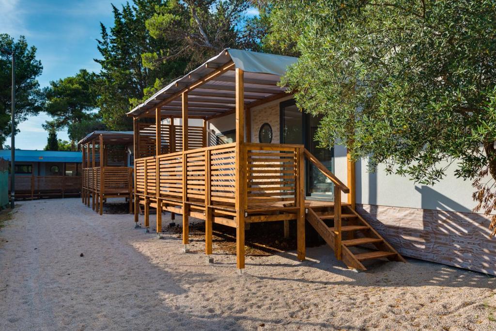 a wooden cabin with a staircase in front of a building at Mobile Home Vodice 14 in Vodice