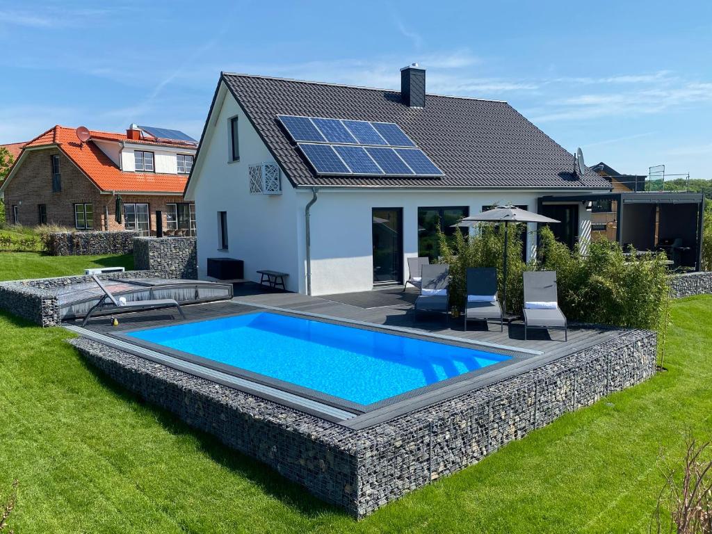 a house with a swimming pool with solar panels on the roof at hey BEACHVILLA in Hohwacht