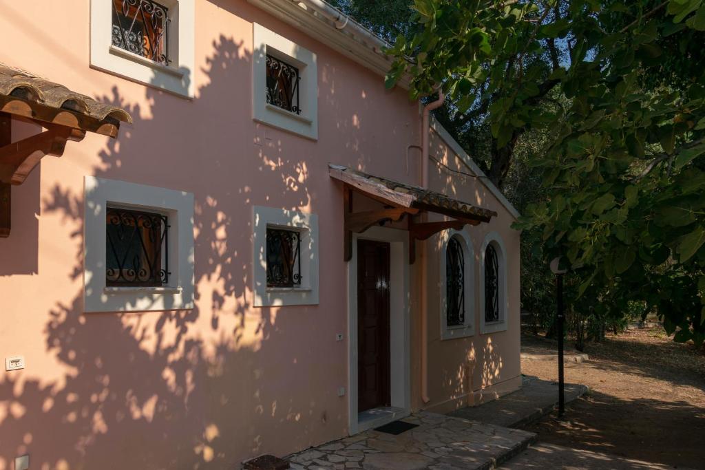 un edificio rosa con un albero di fronte di Villa Olive apartments a Ipsos
