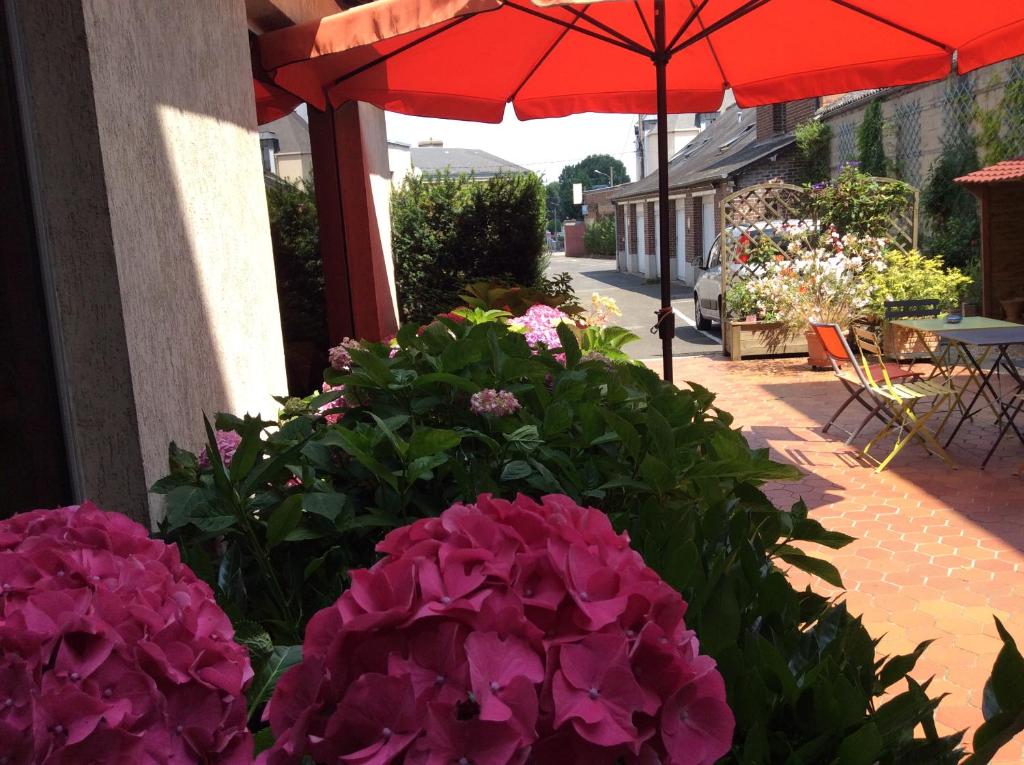 d'un parasol rouge, de fleurs violettes et d'une terrasse. dans l'établissement Hôtel le cygne, à Gournay-en-Bray