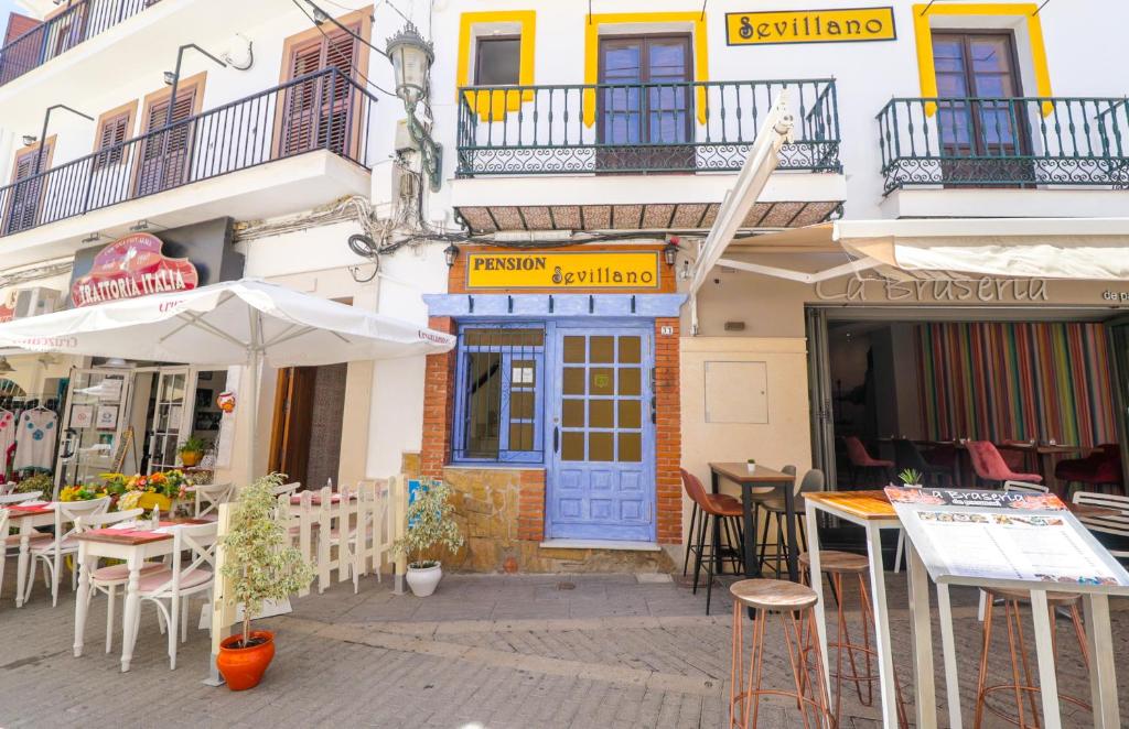 a restaurant with tables and umbrellas in front of a building at Pensión Sevillano in Nerja