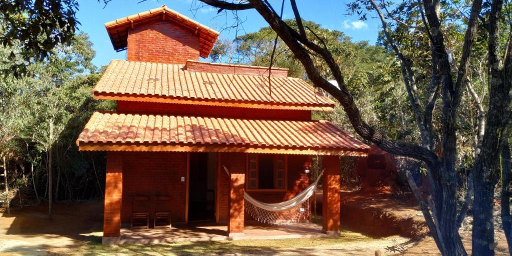 a small brick house with a hammock in front of it at Chalé 1 - Recanto Shambala in São Thomé das Letras