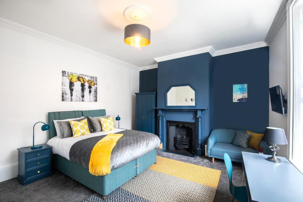 a bedroom with blue walls and a bed and a desk at BrickSage Rooms, King's Lynn South Gate in Kings Lynn