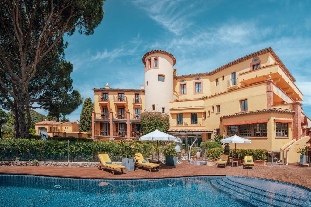 un hotel con piscina frente a un edificio en Ermitage de l'Oasis & Spa - Cannes Mandelieu en Mandelieu-la-Napoule
