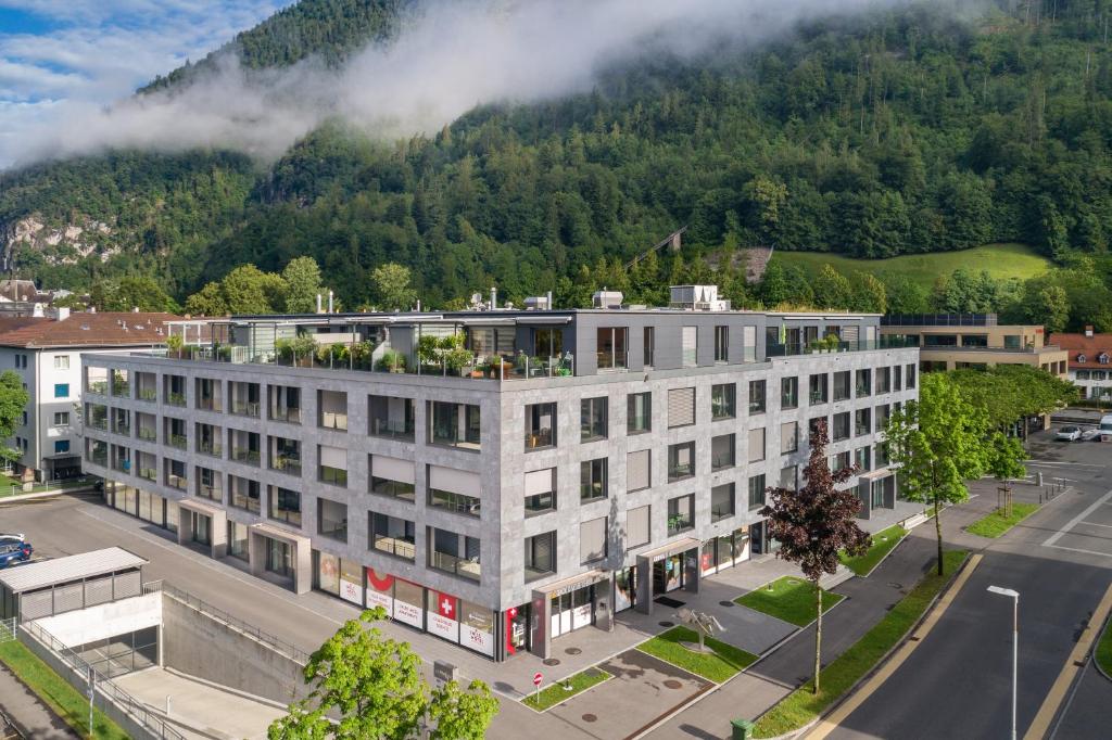 un immeuble situé en face d'une montagne dans l'établissement Swiss Hotel Apartments - Interlaken, à Interlaken