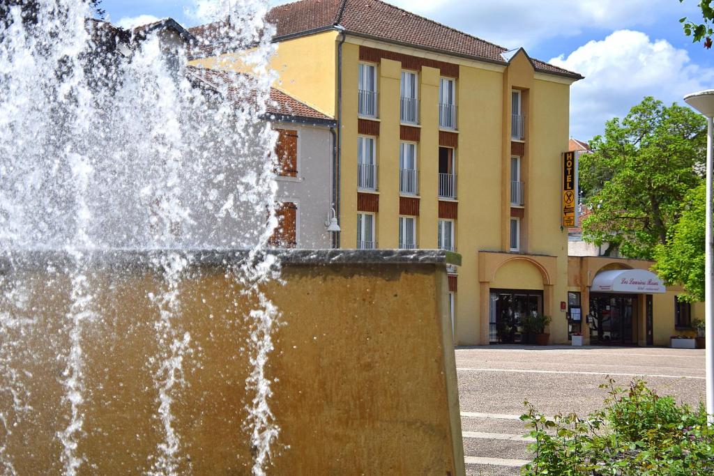 einem Brunnen vor einem Gebäude in der Unterkunft Hotel des Lauriers Roses in Bourbonne-les-Bains