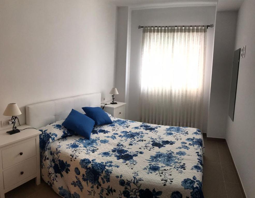 a bedroom with a blue and white bed and a window at Apartamento en Piles Playa in Piles