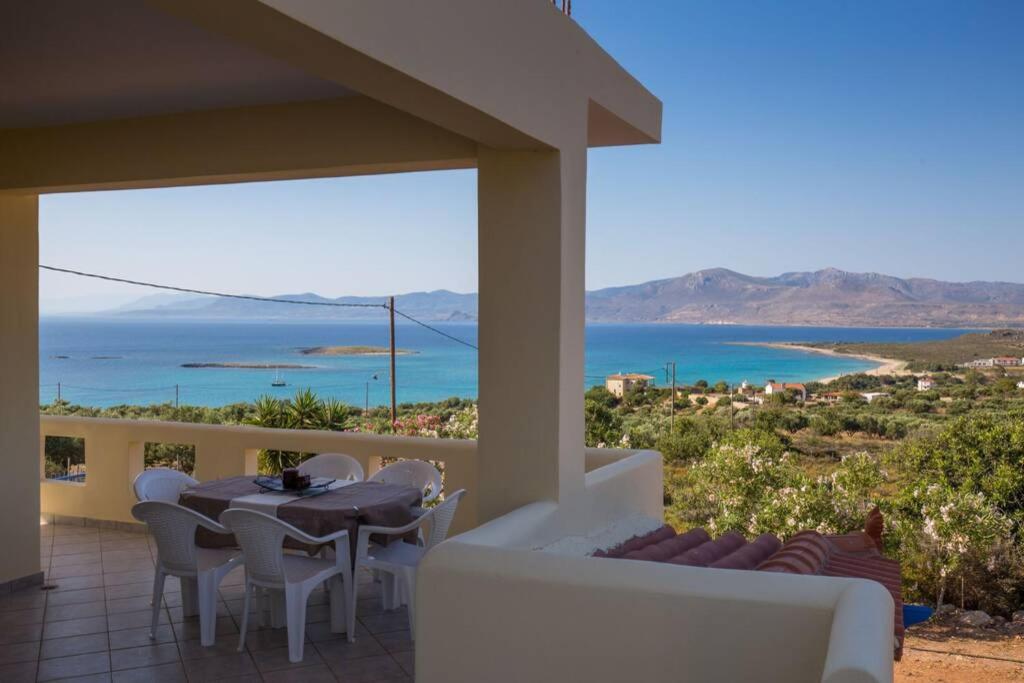 een tafel en stoelen op een balkon met uitzicht op de oceaan bij Elafonisos Amazing View in Elafonisos