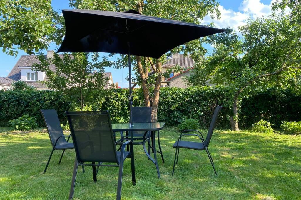 una mesa negra y sillas bajo una sombrilla en Võru Villa, saun, grill, jalgrattad, ideaalne perepuhkus!, en Võru