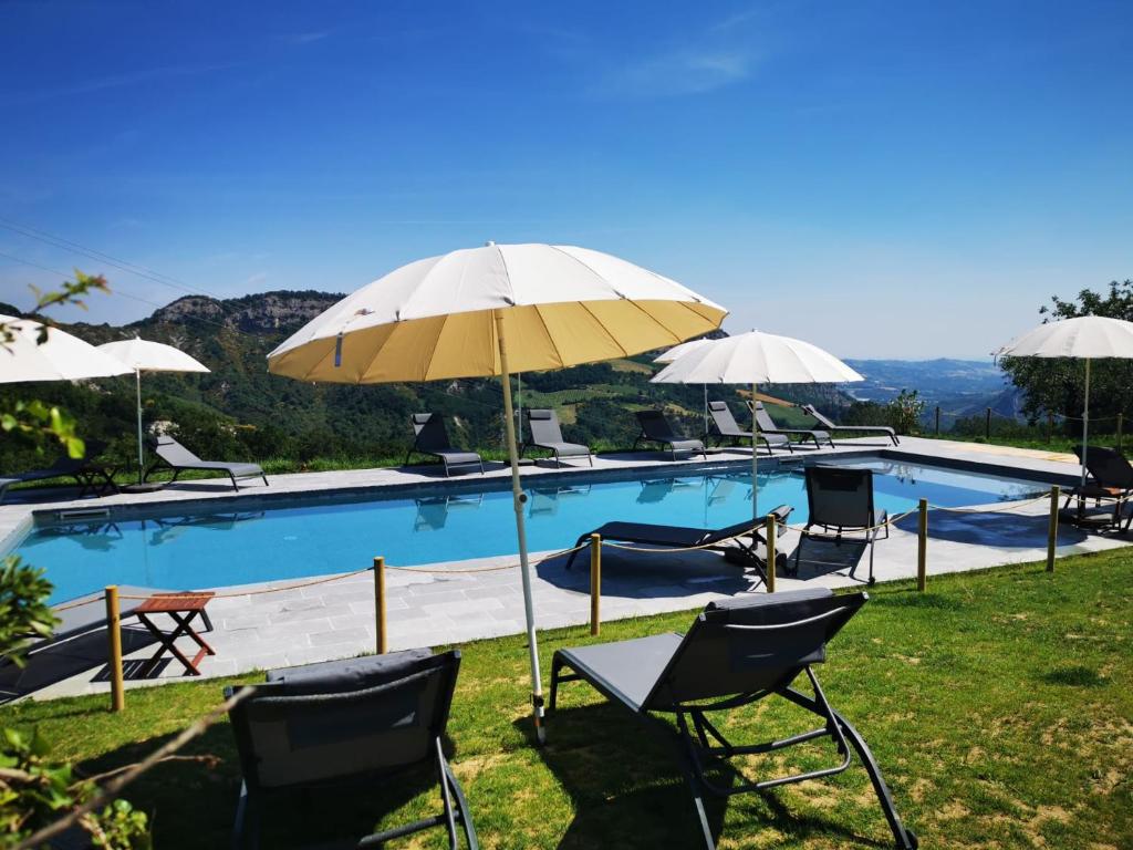 een zwembad met stoelen en parasols in het gras bij Relais Mevigo - Casa Pietra in Rivola