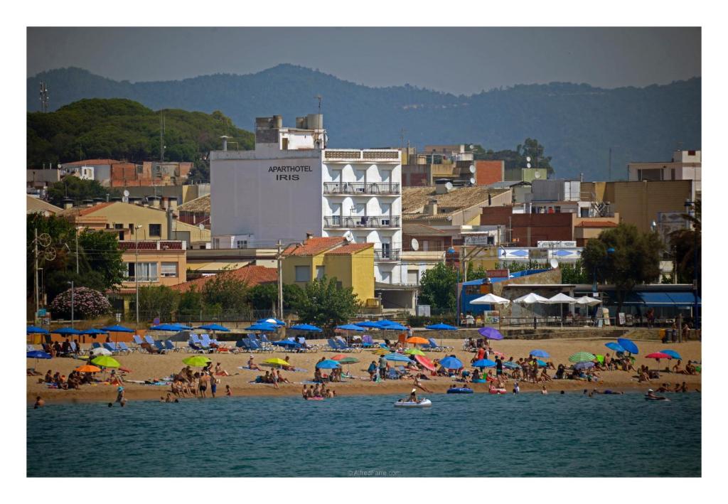 een groep mensen op een strand met parasols bij Aparthotel Iris in Malgrat de Mar