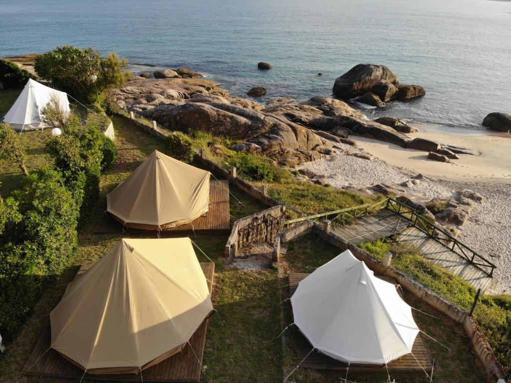 a group of tents on a beach near the water at Camping & Glamping Muiñeira in O Grove