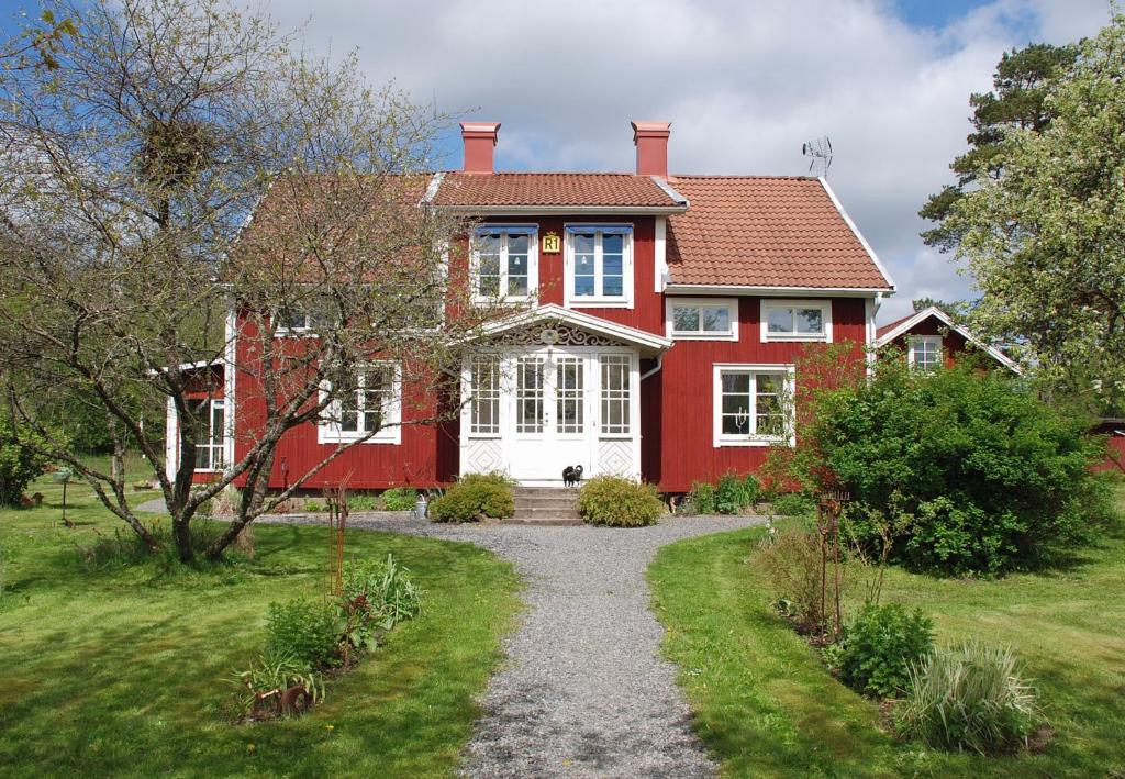 a red and white house with a gravel driveway at Villa Vilan - Countryside Lodging in Skillingaryd