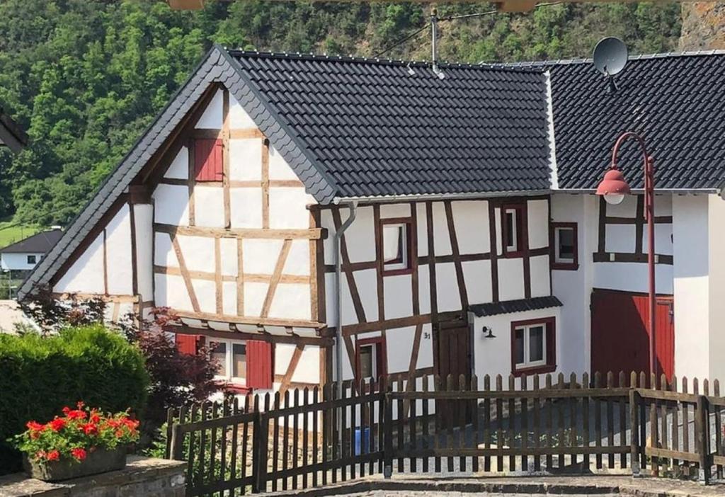a white and black house with a wooden fence at Ferienhaus "Am Backes" in Pützfeld