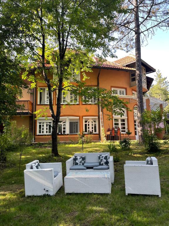 a group of couches in a yard in front of a house at Apartments Micic in Zlatibor