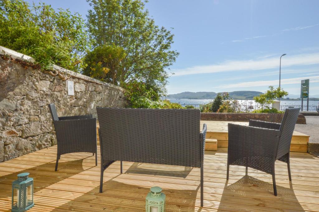 three chairs and a fire hydrant on a wooden deck at No 8 Westbay Apartment in Oban