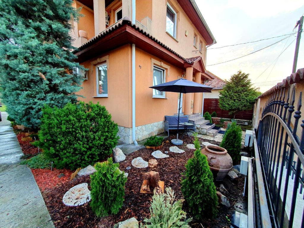 a garden in front of a house with an umbrella at Airport Luxury Apartman 42 in Vecsés