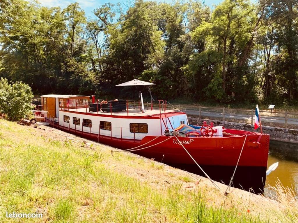 una barca rossa e bianca è ormeggiata in acqua di LES AMIS D'ULYSSE a Chagny