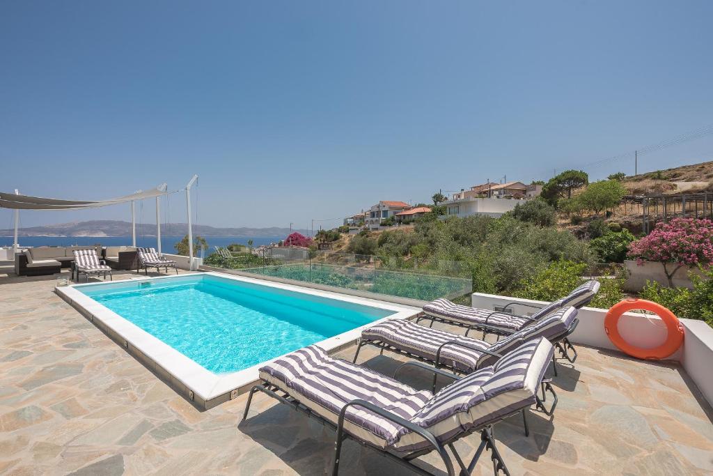a swimming pool with chaise lounge chairs next to a swimming pool at Villa Luna Private Heated Hydro Pool BBQ Beach 4min in Agia Marina Mikrolimanou