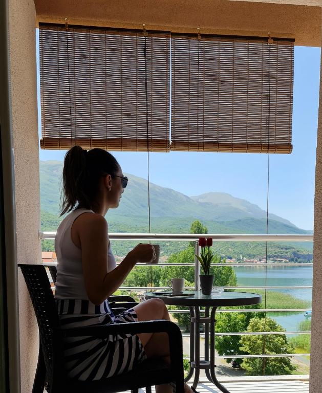 a woman sitting at a table in front of a window at Apartment AXA in Ohrid